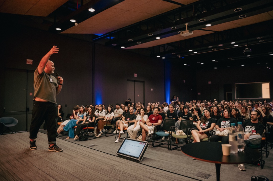 Jaakko Tammela speaking on stage to a full auditorium