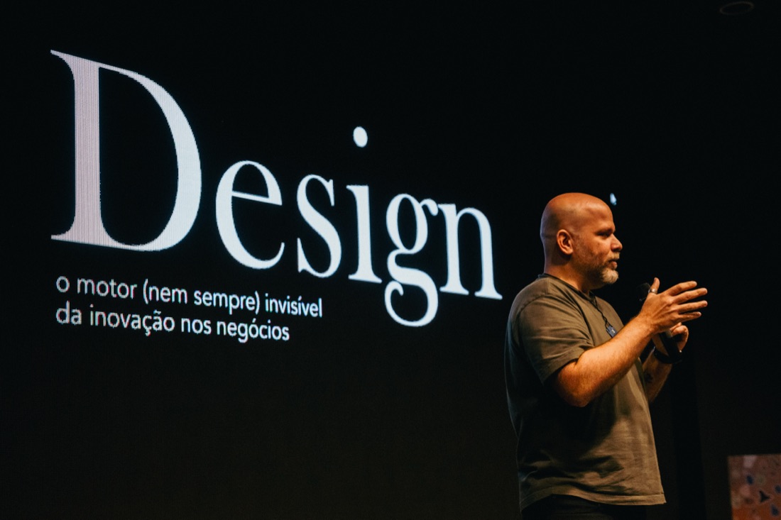 Jaakko Tammela on stage beside a slide reading Design